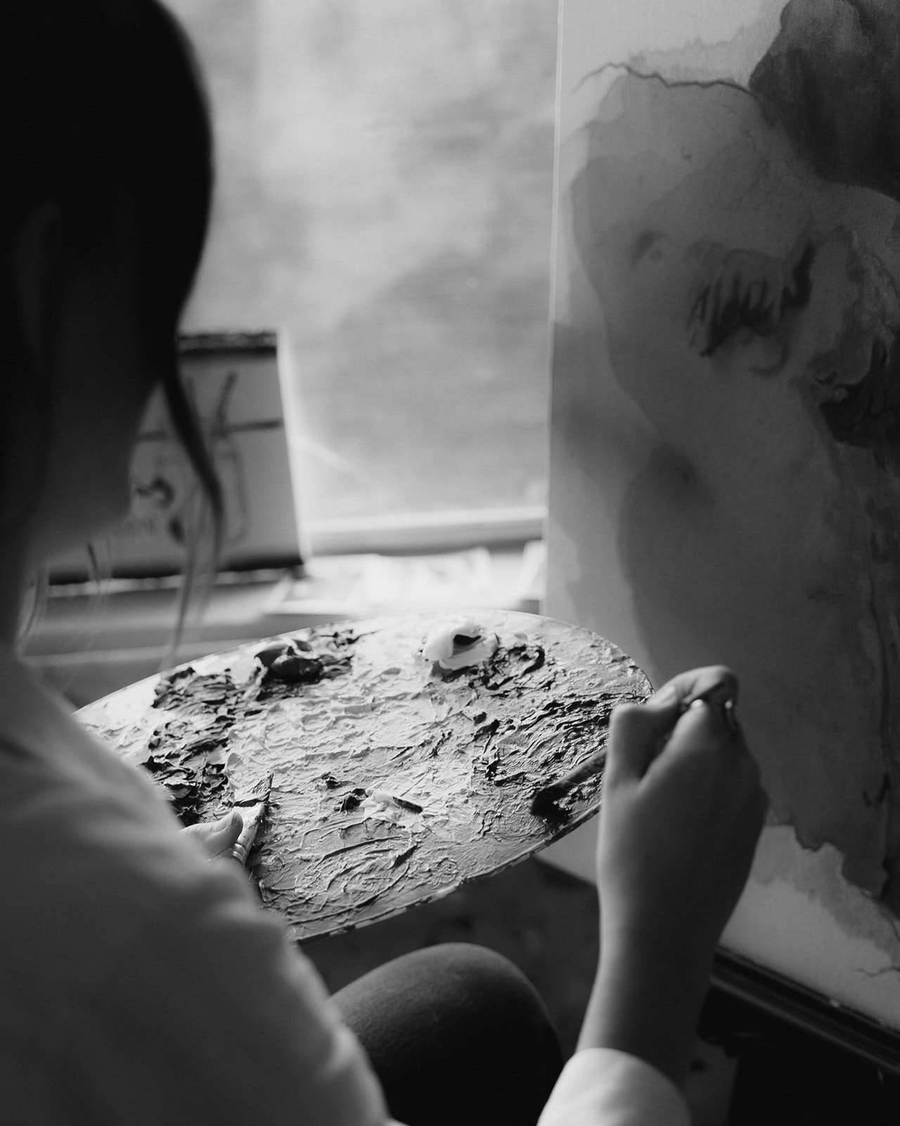 Haley mixing paint on a palette while working in her studio